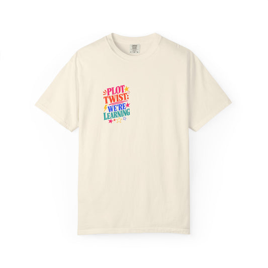 Plot Twist: We're Learning Tee in Ivory, front view - a small left-chest print on a garment-dyed Comfort Colors 1717 tee.