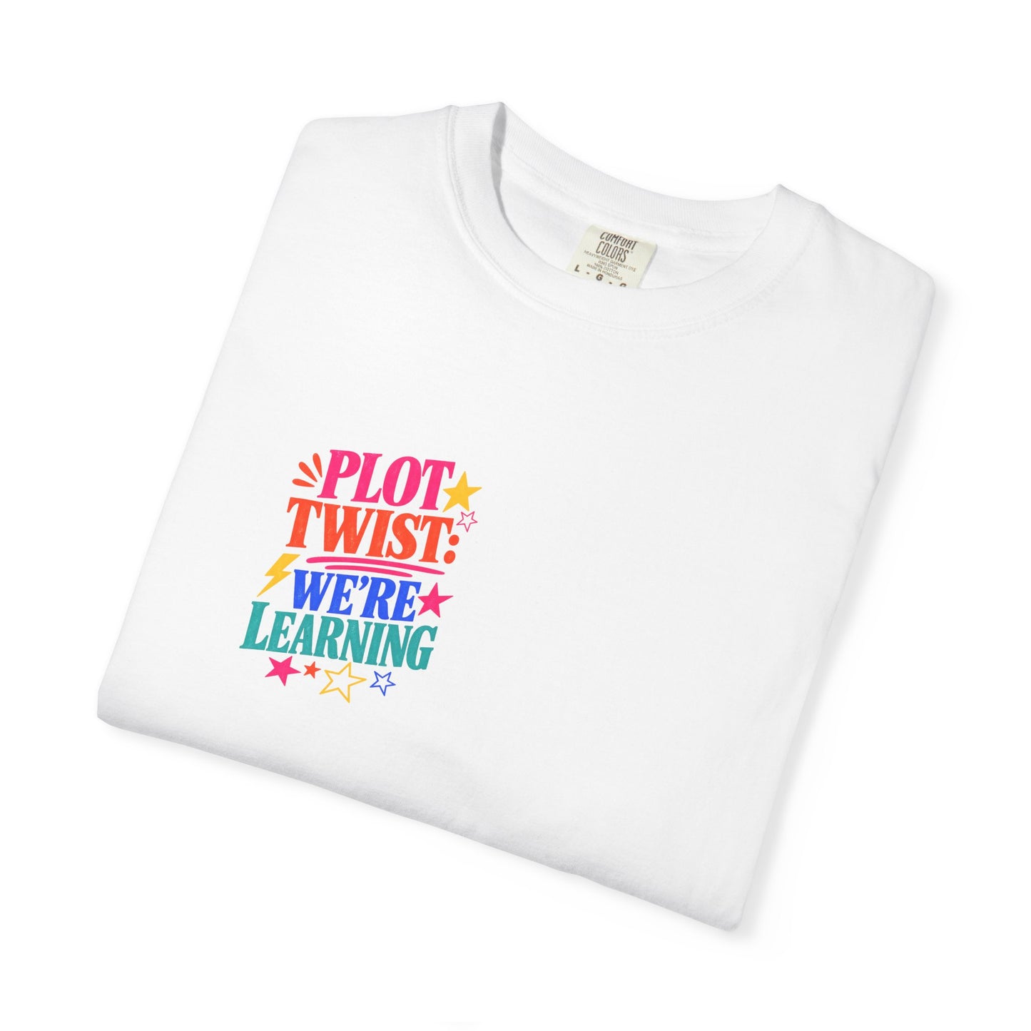 Plot Twist: We're Learning Tee in White, folded flat - a small left-chest print on a garment-dyed Comfort Colors 1717 tee.