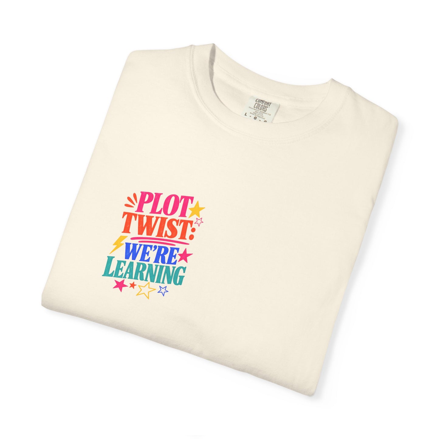 Plot Twist: We're Learning Tee in Ivory, folded flat - a small left-chest print on a garment-dyed Comfort Colors 1717 tee.